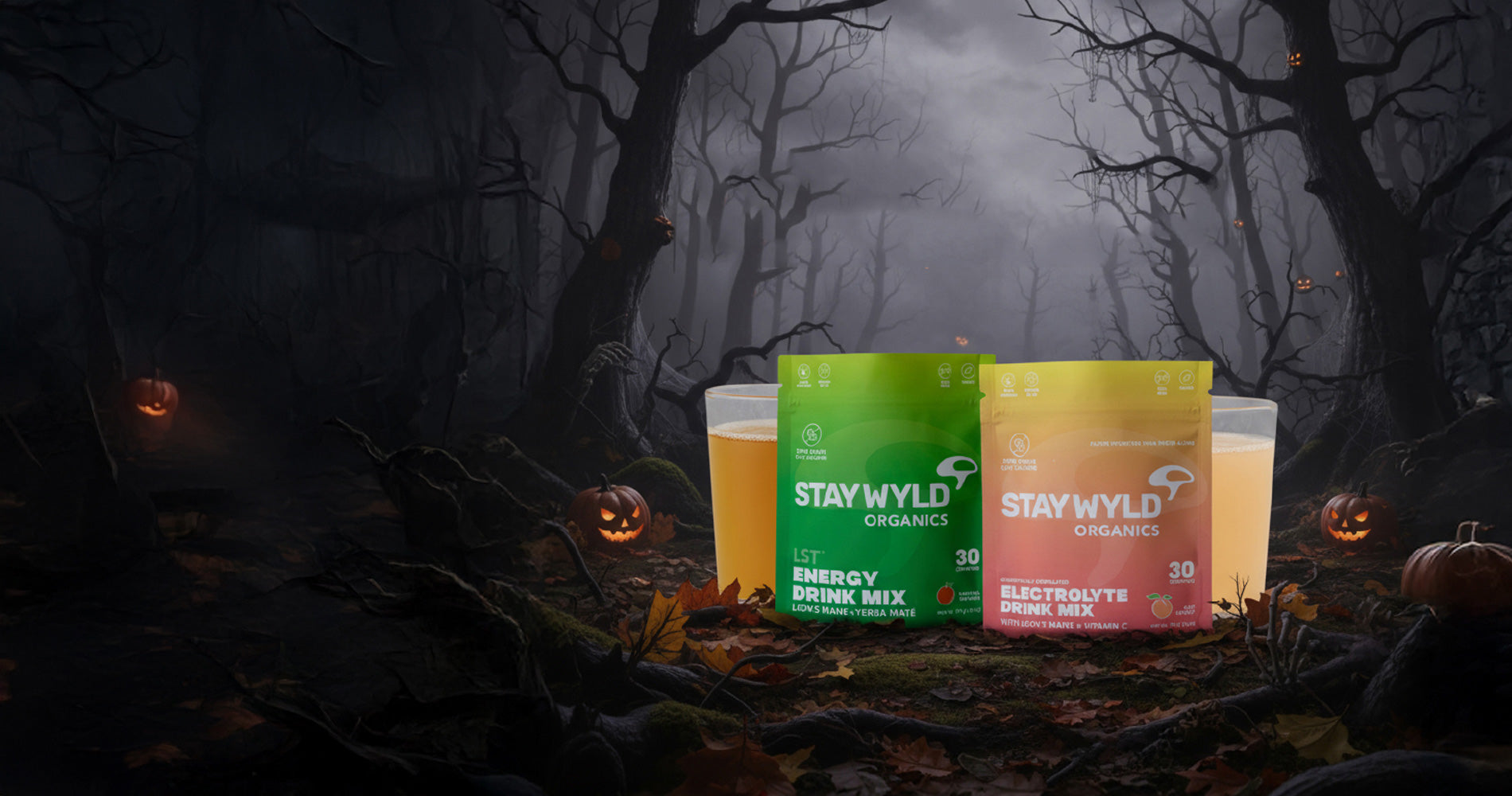 Stay Wyld Organics drink mix containers in a Halloween-themed forest setting with pumpkins and fog.